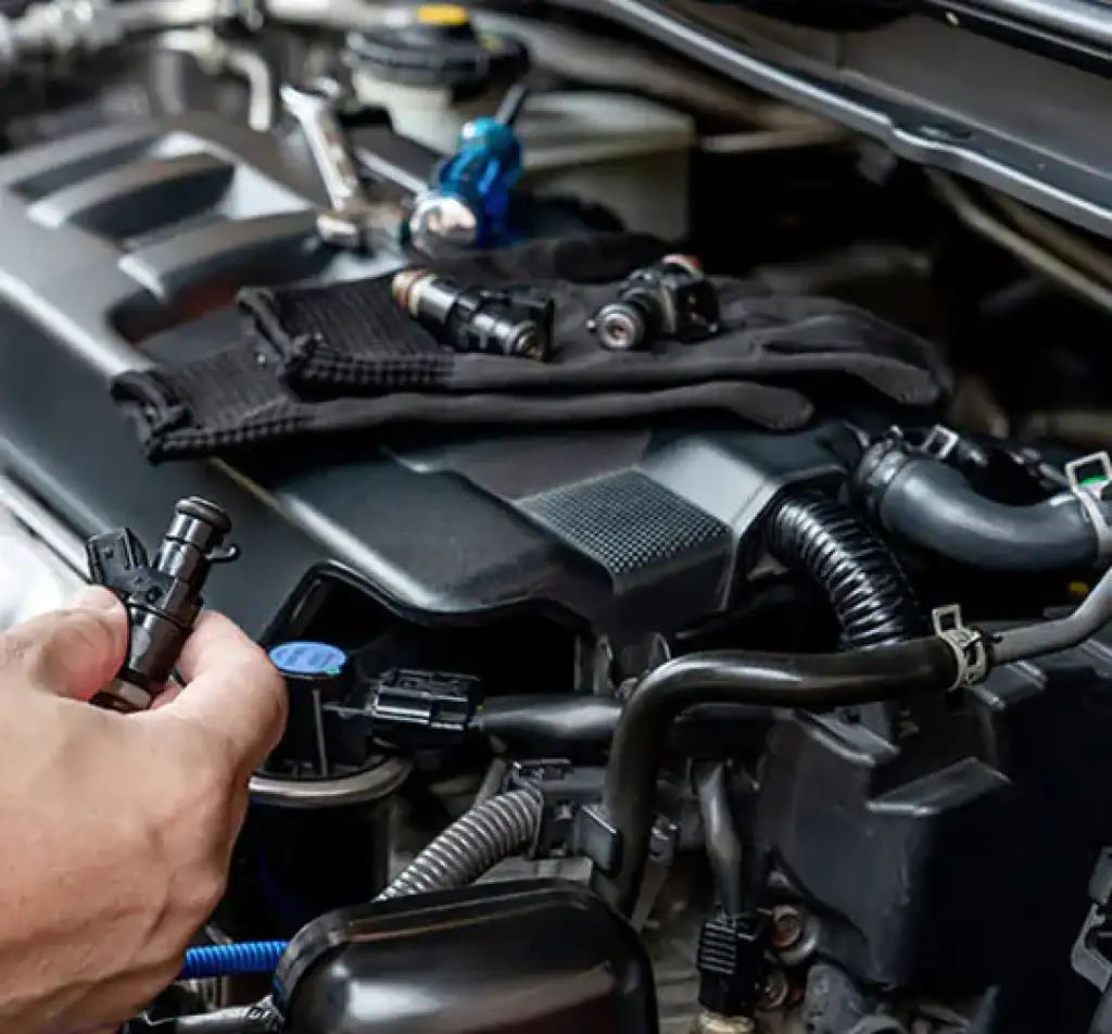 Remplacement d'injecteurs de carburant usagés sur un moteur de voiture lors d'un entretien automobile professionnel.